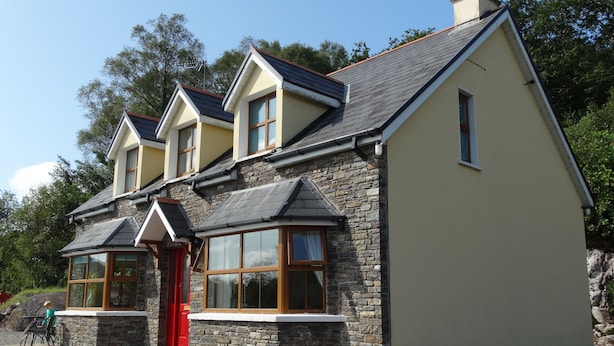 A two-story house with a stone facade, a red door, and multiple windows. - The River House, Nature Reserve Glengarriff (Glengarriff)