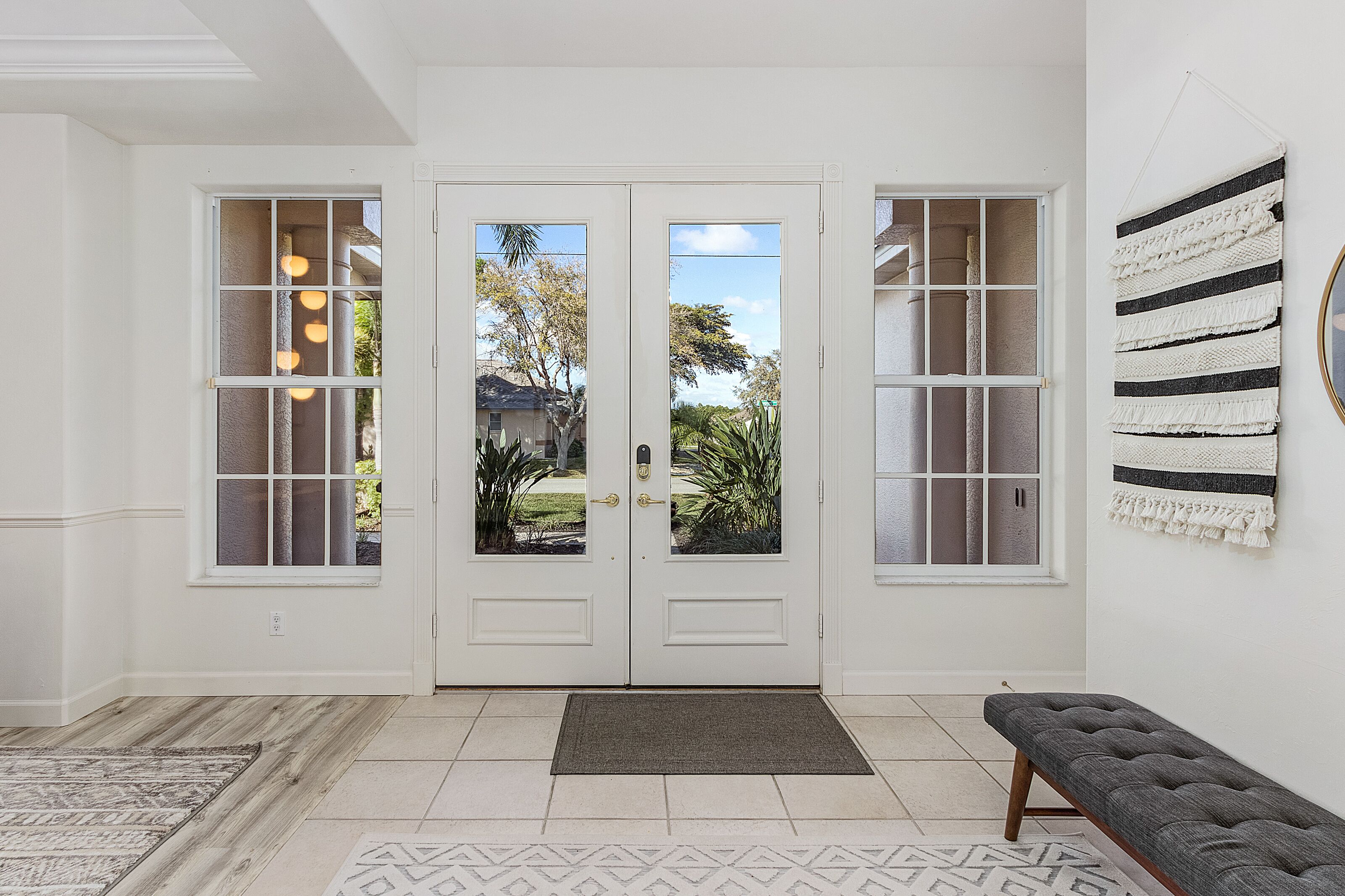 A clean, modern entryway with a double door, a bench, and a view of the outdoors.