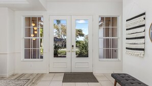 Un ingresso moderno e pulito con una porta doppia, una panca e vista sull'esterno.