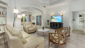 Un soggiorno spazioso con una grande TV, posti a sedere confortevoli e una ventola a soffitto.