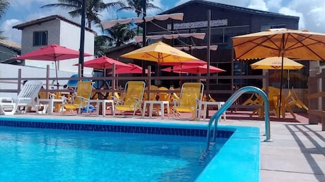 Una piscina al aire libre, sombrillas, sillones reclinables de piscina
