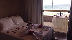 Habitación de hotel con cama, balcón con mesa y vista al mar.