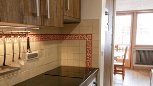 A kitchen with wooden cabinets, a black countertop, and a tiled backsplash. - Fully renovated studio cabin for 2-4 people in Tignes le lac   (Le Lac de Tignes)