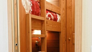 A wooden bunk bed with a ladder, a small shelf, and a red patterned blanket. - Fully renovated studio cabin for 2-4 people in Tignes le lac   (Le Lac de Tignes)