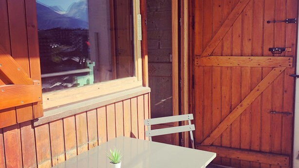 A wooden interior with a white table, a chair, and a view through a window. - Fully renovated studio cabin for 2-4 people in Tignes le lac   (Le Lac de Tignes)