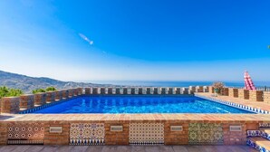 Ein Pool mit Blick aufs Meer, umgeben von Ziegelmauern und gemusterten Fliesen.