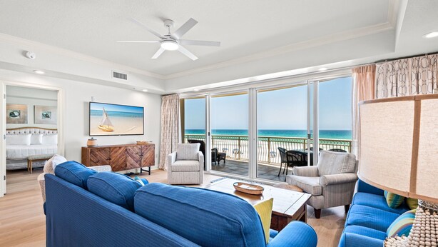 A living room with a large window, a ceiling fan, and a view of the ocean. - Condos directly on the Gulf (Destin)