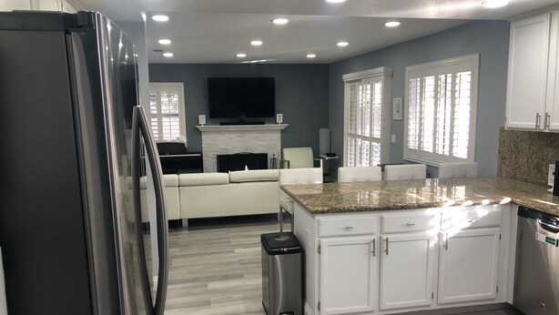 A modern kitchen with white cabinets, a granite countertop, and a stainless steel refrigerator.