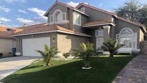 A two-story house with a garage, a well-maintained lawn, and a brick pathway.