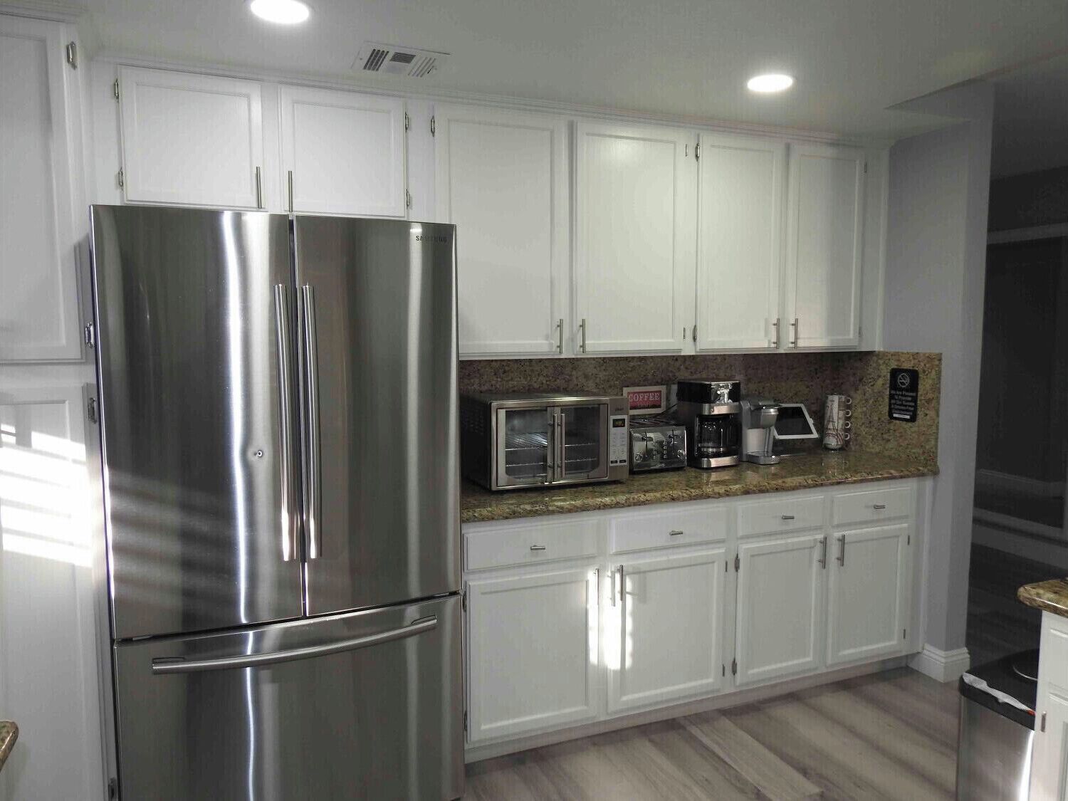 A modern kitchen with white cabinets, stainless steel appliances, and granite countertops.