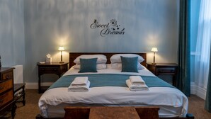 A neatly made bed with two pillows, a bedside table with a lamp, and a wall decoration that reads "Sweet Dreams". - Forrest's Townhouse -  Two adjoining apartments with shared private hallway (Kendal)