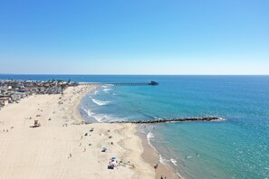A beach with a pier extending into the ocean, sandy shore, and beachgoers.