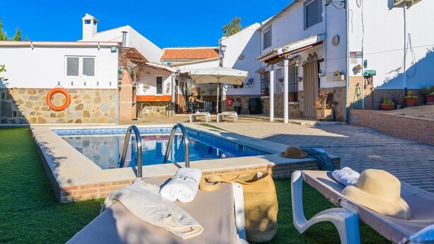A pool area with lounge chairs, a lifebuoy, and a stone wall. - Casa Rural La Cañada Villanueva de Algaidas by Ruralidays (Málaga)