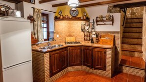 A kitchen with a brick backsplash, wooden cabinets, a sink, and a stove. - Casa Rural La Cañada Villanueva de Algaidas by Ruralidays (Málaga)