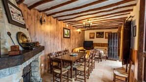 A dining area with a stone fireplace, wooden beams, and a television in the background. - Casa Rural La Cañada Villanueva de Algaidas by Ruralidays (Málaga)