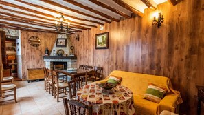 A cozy dining area with wooden walls, a stone fireplace, and a round table with a menu-covered tablecloth.