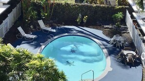 Ein runder Swimmingpool mit einer Metallleiter, umgeben von Liegestühlen und Tischen.
