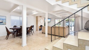 A spacious living area with a fireplace, a dining area with a table and chairs, and a staircase with a railing.