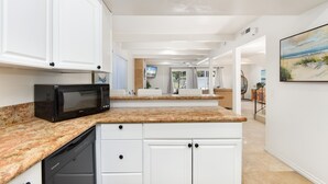 A modern kitchen with white cabinetry, granite countertops, and a built-in microwave.
