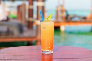 A clear glass with a straw and a slice of lime on a wooden table. - Blue Bird Hotel Boutique (Bacalar)