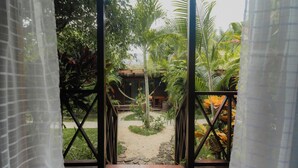 Una terraza de madera que conduce a un jardín con una estructura de techo de paja.