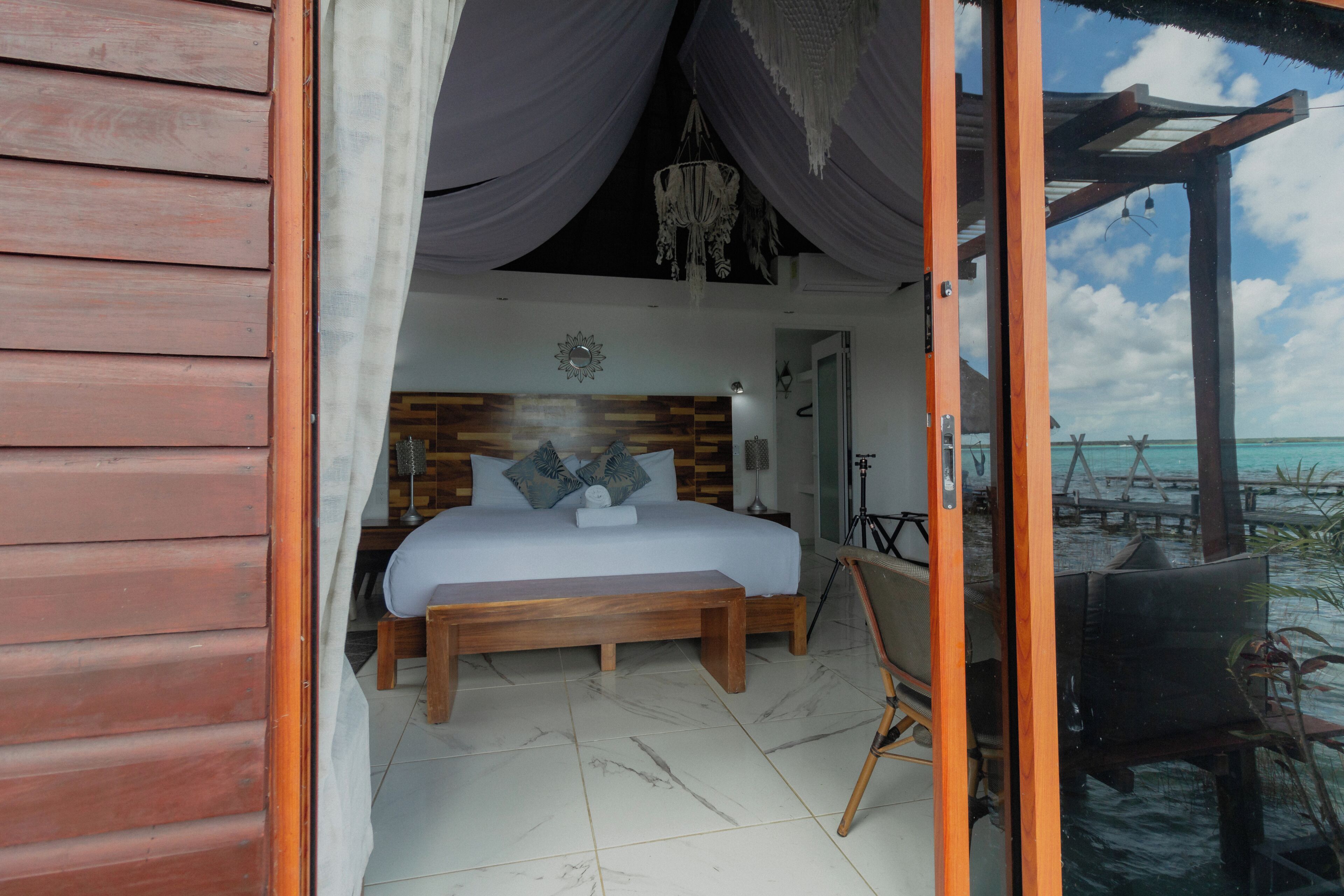 Un dormitorio con una cama de madera, una mesita de noche y vista al océano.