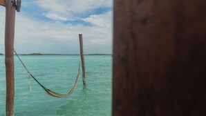 Una hamaca atada entre postes de madera en aguas turquesas cristalinas.