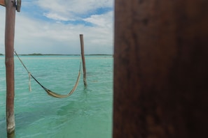 Una hamaca atada entre postes de madera en aguas turquesas cristalinas.