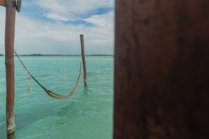 Una hamaca atada entre postes de madera en aguas turquesas cristalinas.
