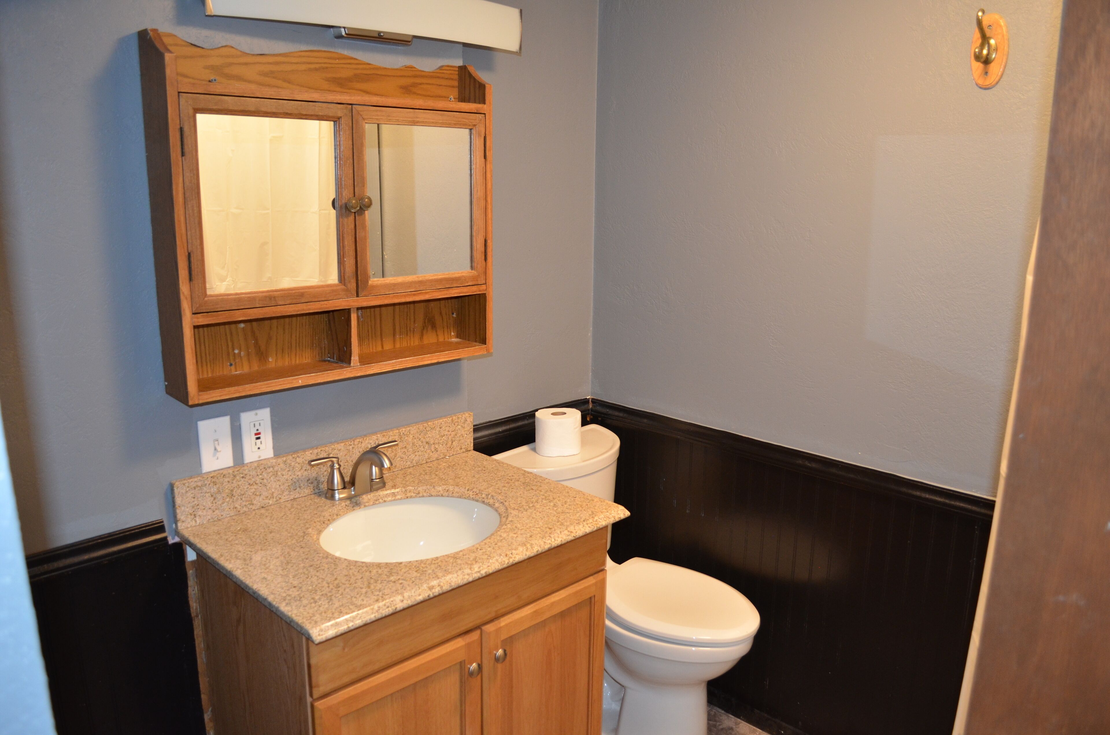 Une salle de bain avec un meuble-lavabo en bois, un évier, un miroir et des toilettes.