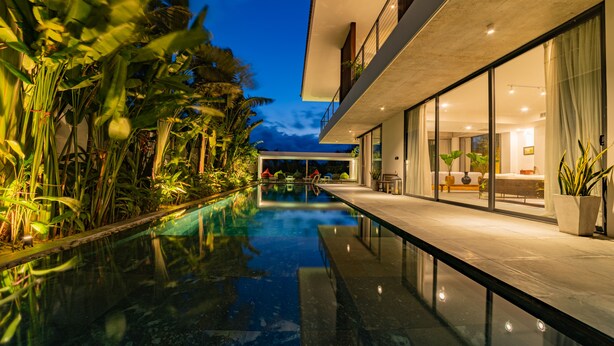 Un bâtiment moderne doté d’une piscine, de portes vitrées et de plantes d’intérieur.