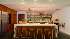 Une cuisine moderne dotée d’un îlot central, de tabourets en bois et d’une variété d’ustensiles de cuisine.