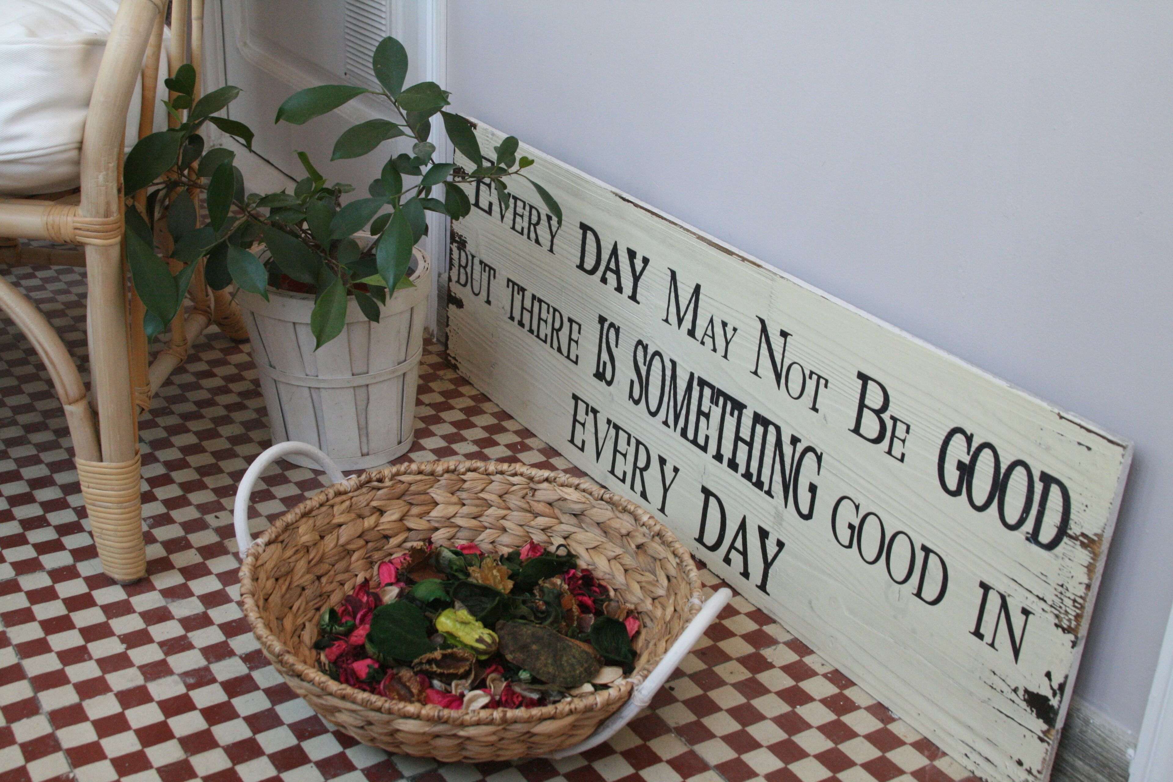 Een rieten mandje gevuld met gedroogde bloemen en een bordje met de tekst: 'Niet iedere dag is goed, maar elke dag is er iets goeds in.'