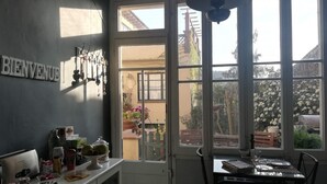 Una cocina con comedor, un cartel 'BIENVENUE', una ventana con vistas al jardín y un ventilador de techo.