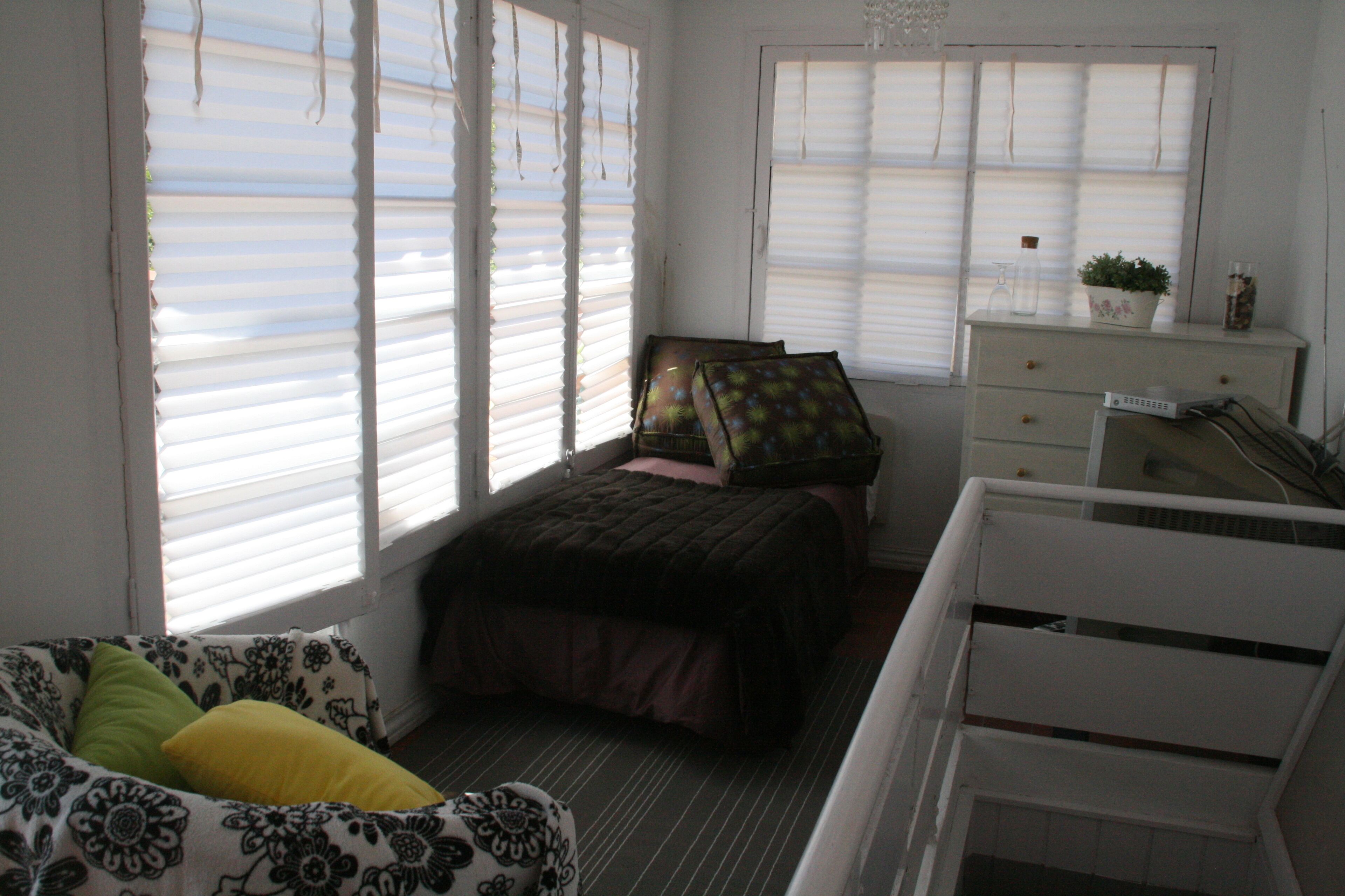 Un dormitorio con cama, cómoda y ventana con persianas.