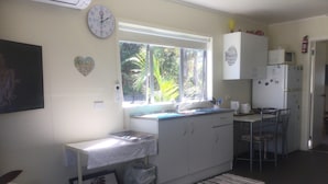 A compact kitchen with a window, a sink, a refrigerator, and a dining area.