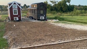 A rural setting with two wooden houses, one red and one brown, with gravel paths and a dirt area in the foreground. - Waterfront RV LOT A (Willis)