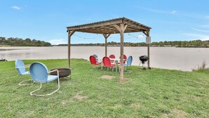 A gazebo with outdoor seating and a grill, overlooking a lake. - Waterfront RV LOT A (Willis)