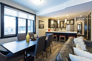 A modern kitchen with dark cabinets, a central island, and a dining area with a table and chairs.