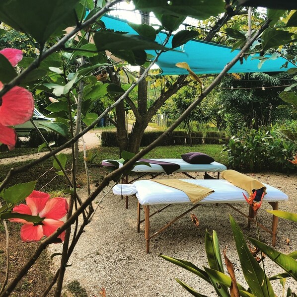 A garden with a gazebo, two massage tables, and a variety of plants.
