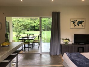 A modern room with a dining area, a bed, a TV, and a world map on the wall. - Modern and bright bungalow, tucked away, nature all around (Tamarindo)