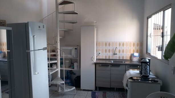 A kitchen with a refrigerator, microwave, sink, and a small table with a kettle. - House 2 people with sea view 15 minutes from the beach, (São José)