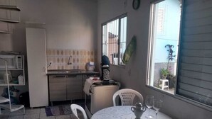 A compact kitchen with a microwave, sink, and a small dining area with a table and chairs. - House 2 people with sea view 15 minutes from the beach, (São José)