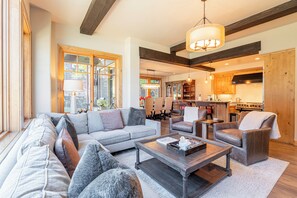 A spacious living area with a sofa set, a coffee table, and a dining area with chairs and a table.