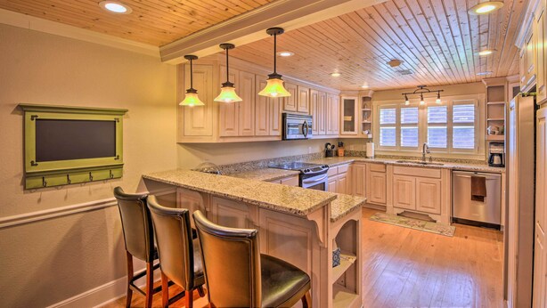 A kitchen with wooden ceiling beams, pendant lights, a granite countertop, and bar stools. - Serving Southern Charm at this Clarkesville House! (Clarkesville)