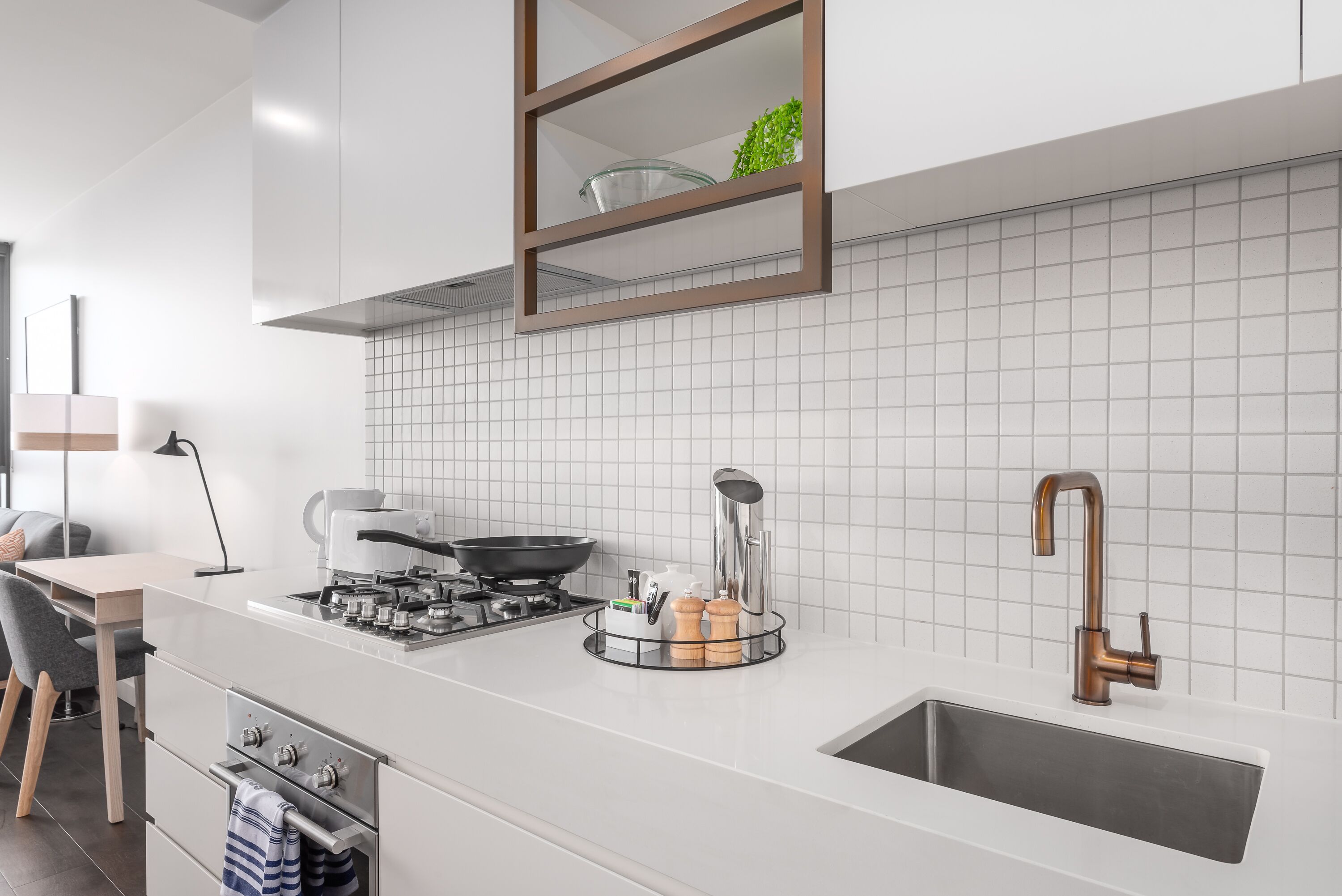 Eine moderne Küche mit einem Gasherd, einem Spülbecken und einer Arbeitsplatte mit einer Glasbowl und Pfefferstreuern.
