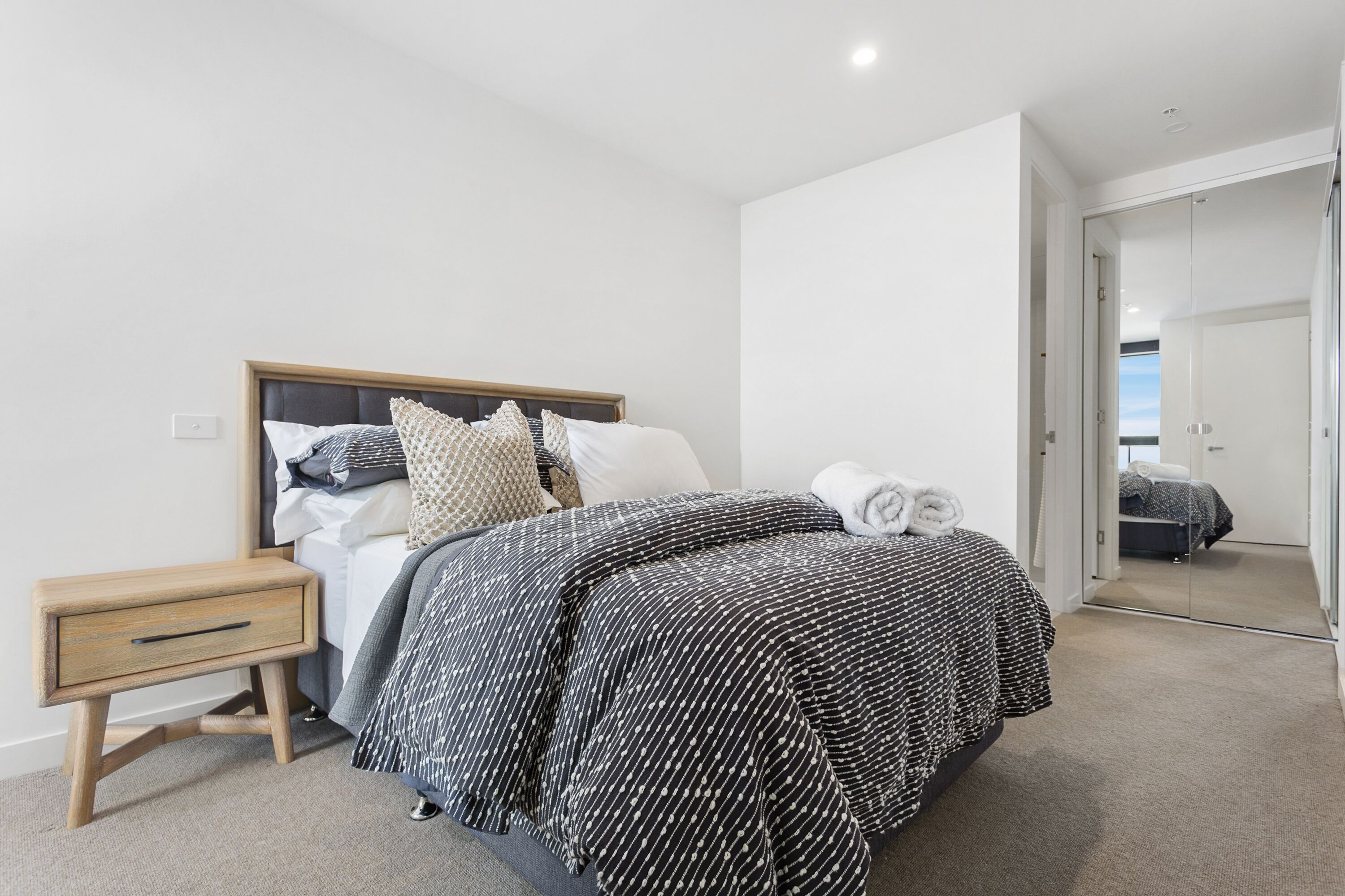 Un dormitorio con cama, mesita de noche y espejo.