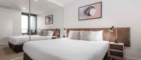 Una habitación de hotel moderna con una cama grande, mesitas de noche, un espejo y un cuadro enmarcado en la pared.