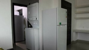 Una cocina con refrigerador, lavadora y microondas.