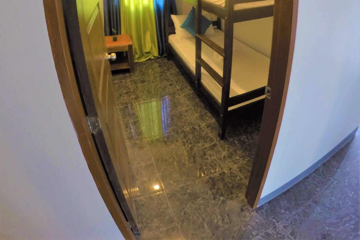 A narrow corridor leading to a room with a bunk bed, a small table, and a curtain.